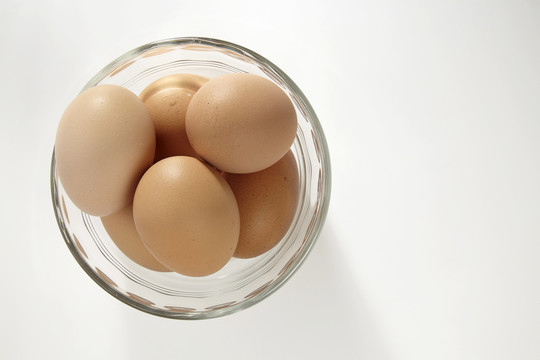 白色背景上装满鸡蛋的玻璃碗