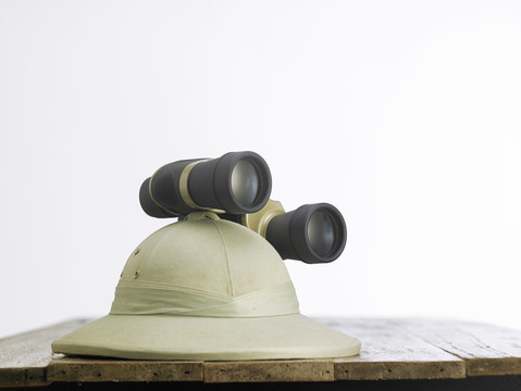 木桌上戴着一顶带双筒望远镜的旧殖民地帽子