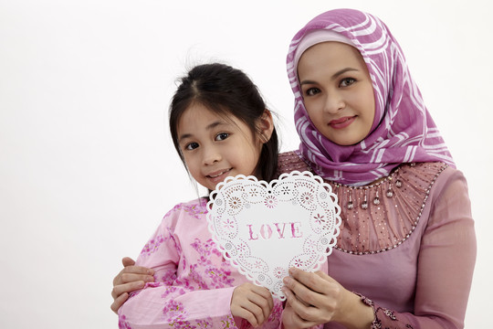 马来妇女带着女儿一起举着心形横幅