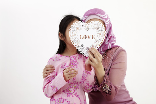 马来妇女带着女儿一起举着心形横幅