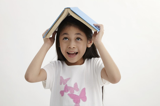 可爱的小女孩头上抱着书