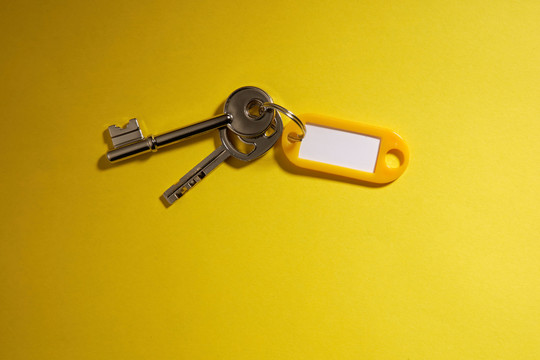 空白标签和黄色背景上隔离的钥匙