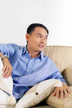 一个穿着蓝色衬衫的男人躺在沙发上微笑着