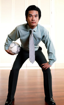 一个穿着西装拿着足球冒充守门员的男人