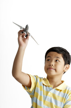 在白色背景上玩玩具飞机的男孩