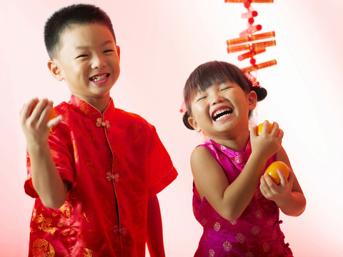 两个孩子抱着桔子笑得很开心