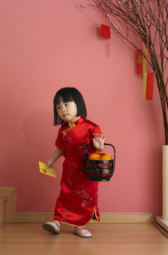 一个中国女孩拿着一桶桔子