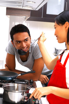 男人看着他的女朋友在厨房做饭
