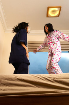 两个穿着睡衣的女人在床上跳跃的低角度视图