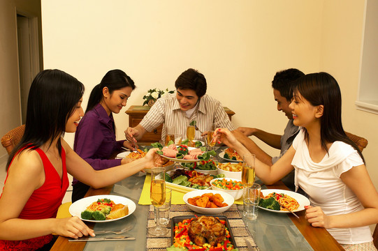 一群男人和女人在餐桌上吃饭