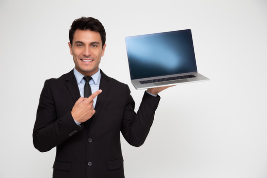 年轻的商人拿着一台笔记本电脑，用手指着笔记本电脑的屏幕，屏幕上有复制空间，可以在线展示应用程序、网站