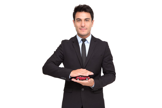 一位身着西装、手持玩具车、与世隔绝地站在白色背景、汽车保险和汽车服务理念上的迷人商人的肖像