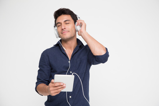 在平板电脑播放列表歌曲应用程序中，帅气的年轻白人男子戴着耳机听音乐