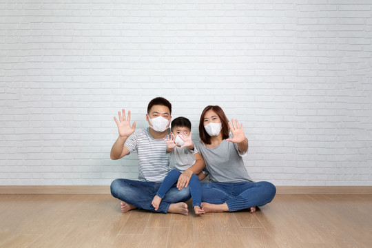 亚洲家庭佩戴防毒面具，并显示停止手势