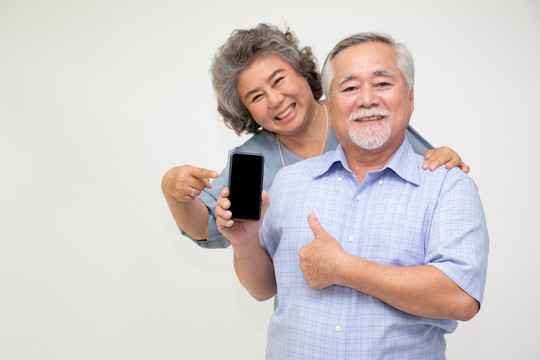 亚洲夫妇高级女性展示或展示手机应用程序，在白色背景上隔离