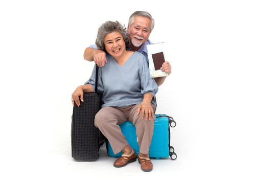 亚洲资深夫妇坐在白色背景下的旅行袋上，旅行者和旅游理念相互隔离