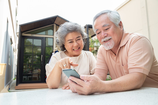 亚洲老年夫妇通过手机视频通话聊天、老年智能技术和在线行动保持联系的概念