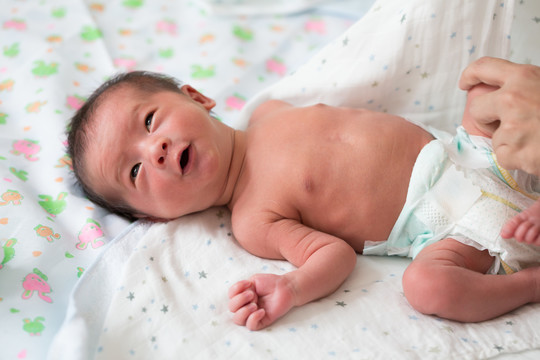 亚洲男婴在床上洗澡后穿尿布，十天大