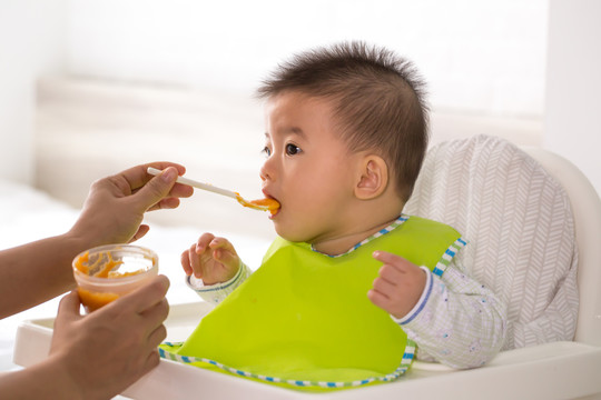 妈妈正在给她的亚洲儿子喂液态食物