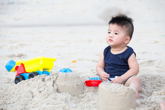 一岁男孩玩沙子，带着孩子去海滩
