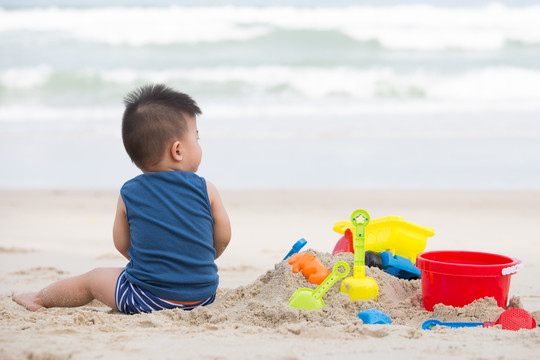 一岁男孩玩沙子，带着孩子去海滩