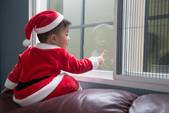 圣诞节那天，婴儿穿着圣诞老人的衣服坐在窗前