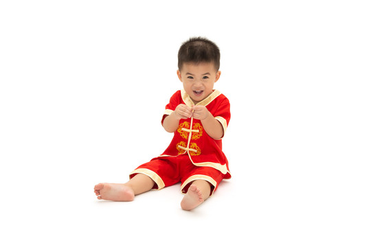 亚洲男婴用手指坐着展示迷你们的心，穿着白色背景上的中国传统套装，为中国新年概念装扮，一岁六个月的婴儿