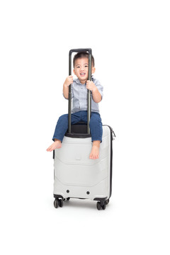 快乐亚洲男婴坐在白色背景上的旅行袋或手提箱上，旅行和新冒险儿童旅客家庭旅行概念，一岁六个月大的模型