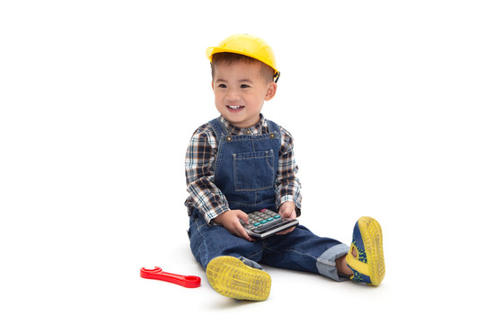 亚裔泰国男婴，身穿工程服，头戴安全帽，手持白色背景的计算器，建筑工人概念，一岁六个月大