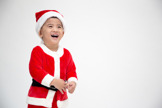 快乐的亚洲男婴穿着白色背景上的圣诞老人的圣诞服装欢笑