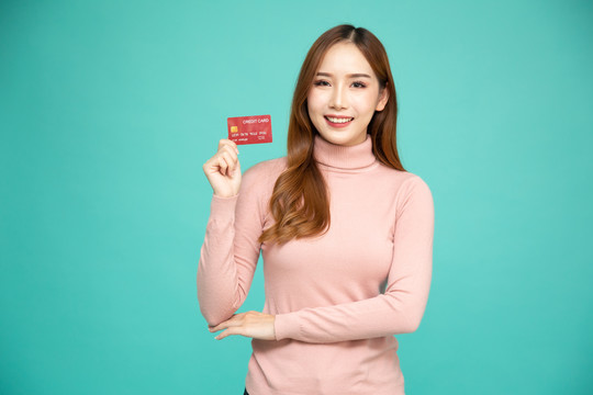 亚洲女性微笑、展示、出示信用卡进行支付或支付在线业务、向商户付款或作为商品、持卡人或持卡人的现金预付