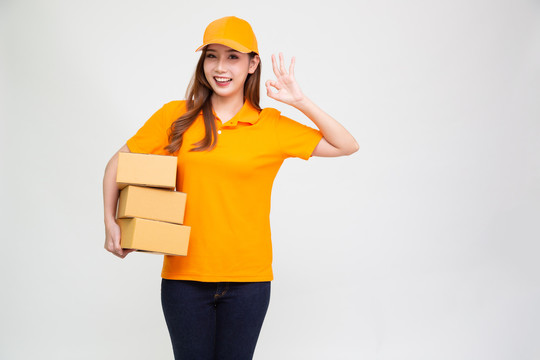 亚洲女送货员手持包裹盒，身穿橙色制服，白色背景隔离