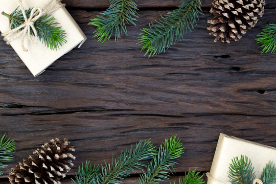 圣诞和新年快乐构图的俯视图、礼品盒、松果、木质背景上的杉木树枝以及文本的复制空间