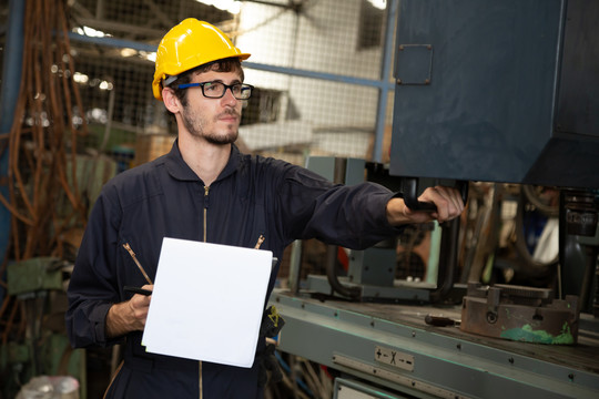 工厂工程师戴黄色安全帽，检查机器，年度维护概念
