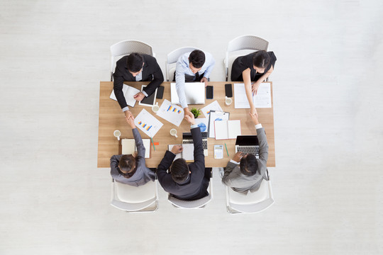 商务人士在团队会议期间坐在会议桌旁握手的俯视图，创业者在团队谈判中握手达成交易开始合作团队合作空白处