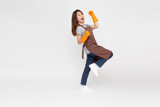 亚洲年轻女子站着的肖像，在清洁过程中戴着橙色橡胶手套保护双手，隔离在白色背景上