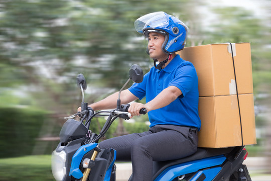 快递员用摩托车或滑板车运送包裹箱。快速快递概念