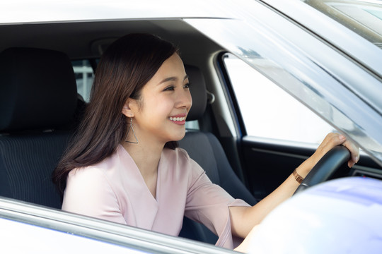 亚洲女性在开车旅行的过程中，带着快乐的积极表情开怀大笑，人们享受着欢笑的交通和轻松快乐的女性路途度假