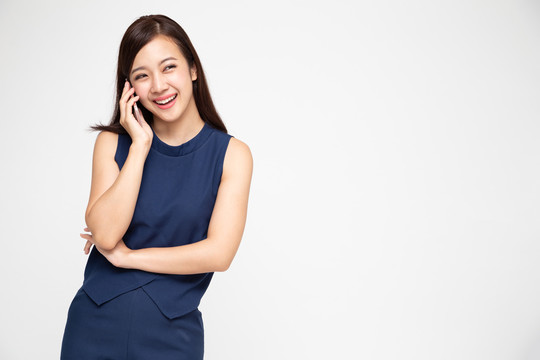 亚洲女性在白色背景下，一边打电话一边微笑，这是电话交谈的概念