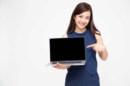 年轻的亚洲女性在白色背景上展示笔记本电脑，并将手指指向笔记本电脑的黑色屏幕，屏幕上有用于在线展示应用
