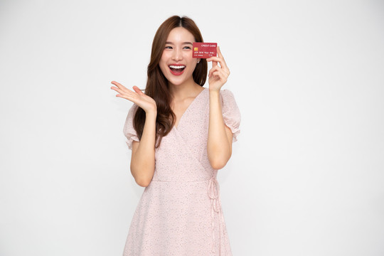 年轻美丽的亚洲女子微笑着拿着白色背景上的信用卡