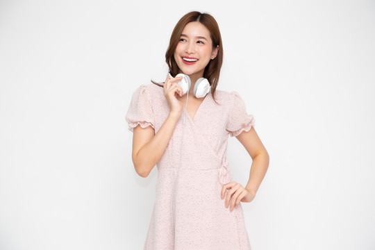 亚洲年轻女子戴着白色背景的耳机听音乐