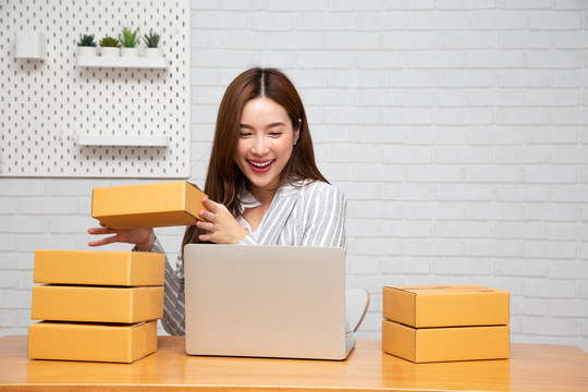 年轻的亚洲企业家，青少年在线企业主在家工作，女性包装产品，客户从网站订购，作为包裹交付，使用服务包裹