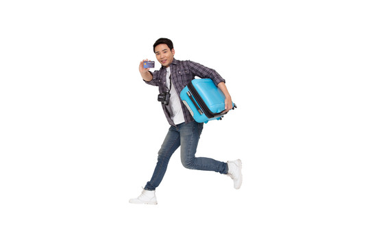年轻的亚洲男子带着手提箱和信用卡在白色背景下跳跃，旅行和旅游理念