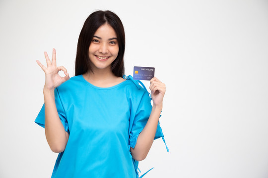 年轻的亚洲美女患者在白色背景上展示个人意外保险信用卡和ok标志，PA和健康索赔服务理念