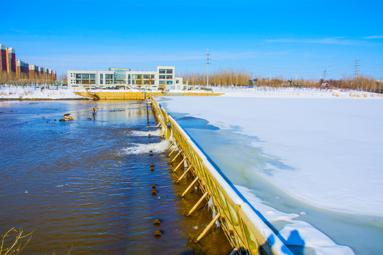 白色三层独楼与河道水坝雪地