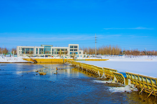 白色三层独楼与河道水坝雪景