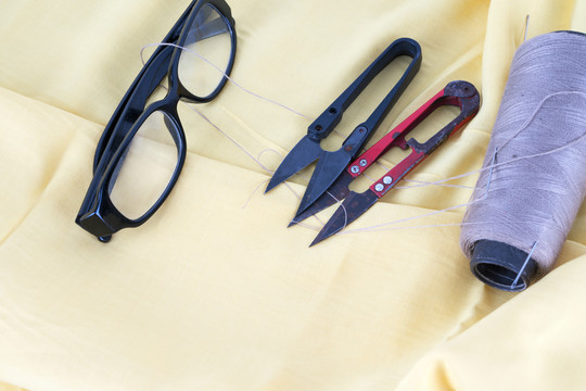 黄色布料上的裁剪缝制工具和眼镜
