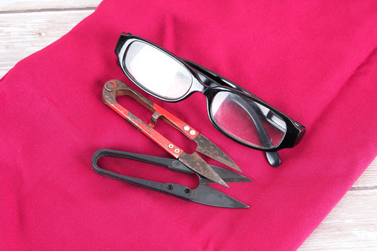 红色布料上的剪刀和眼镜