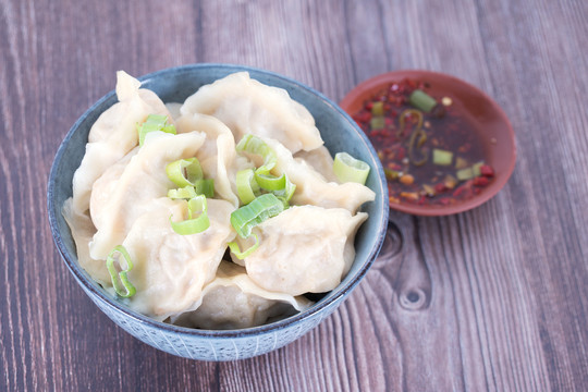 俯视一碗煮熟的饺子和一盘蘸料